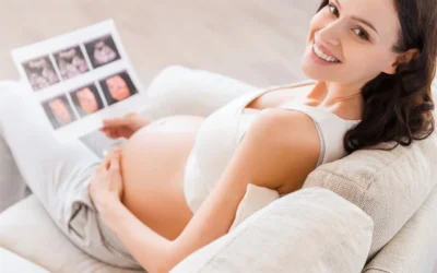 Pregnant woman smiling while holding 3D ultrasound images, showcasing prenatal bonding and excitement for upcoming parenthood.